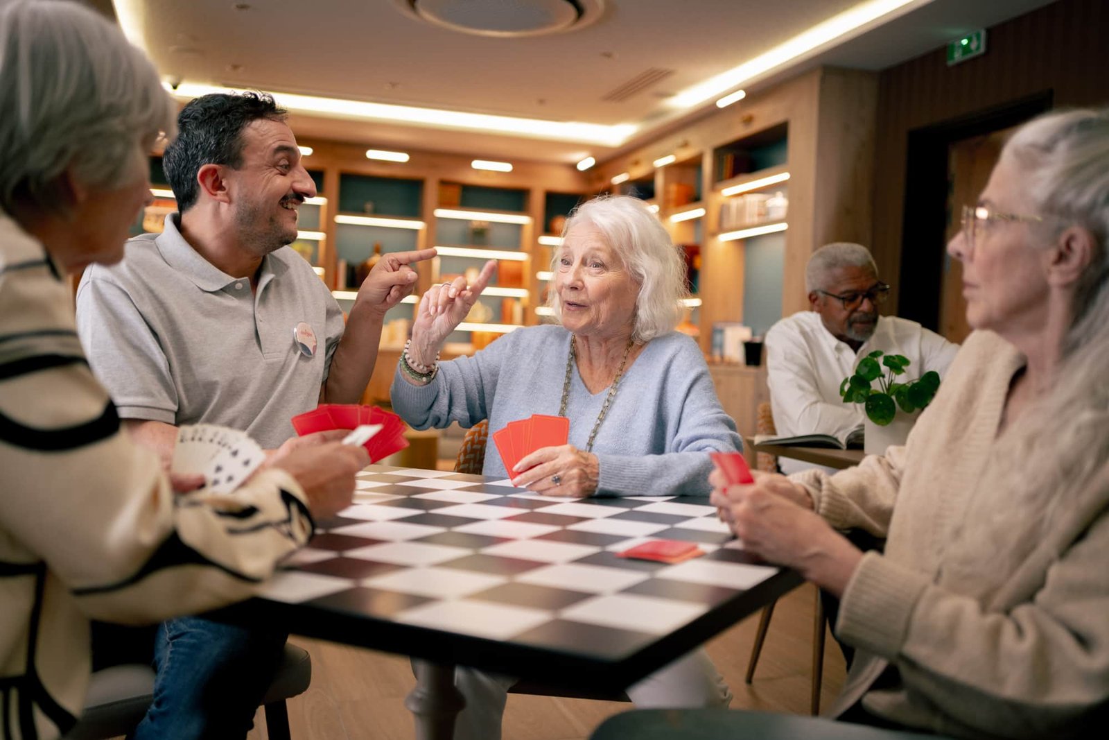 Une résidente seniors joue aux cartes avec un coordinateur Nohée