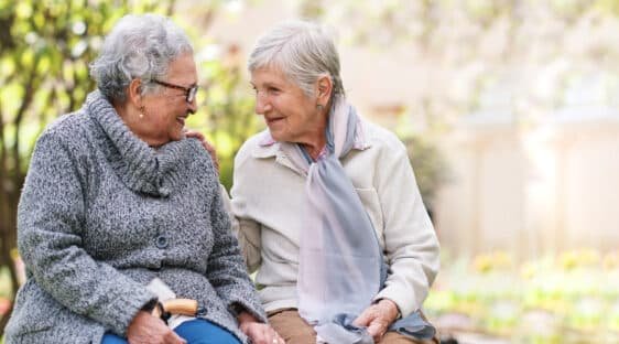 Deux amis seniors discutant dans le jardin de la résidence senior Nohée.