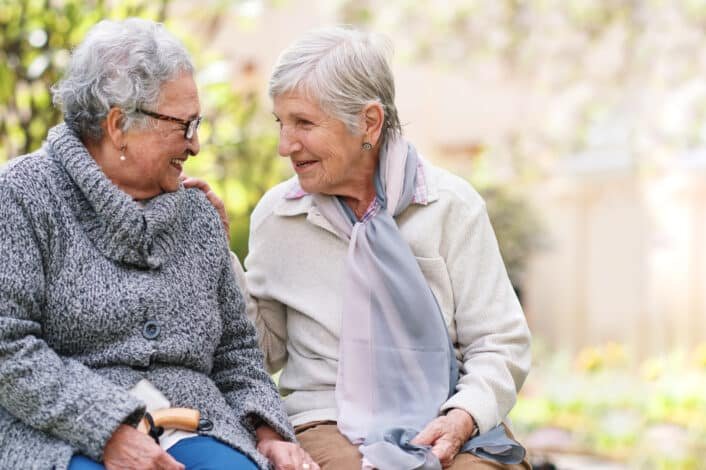 Deux amis seniors discutant dans le jardin de la résidence senior Nohée.
