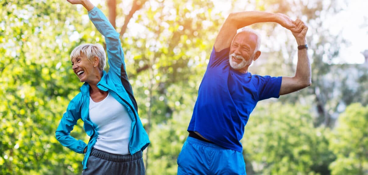 Happy fit senior couple exercising in park. - Nohée